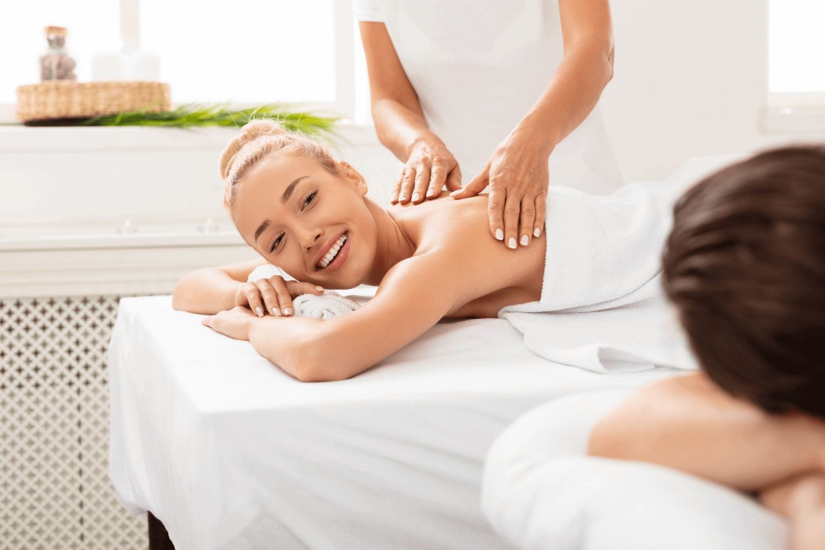 wife-smiling-to-husband-during-couples-massage-rel-U3XWU2A
